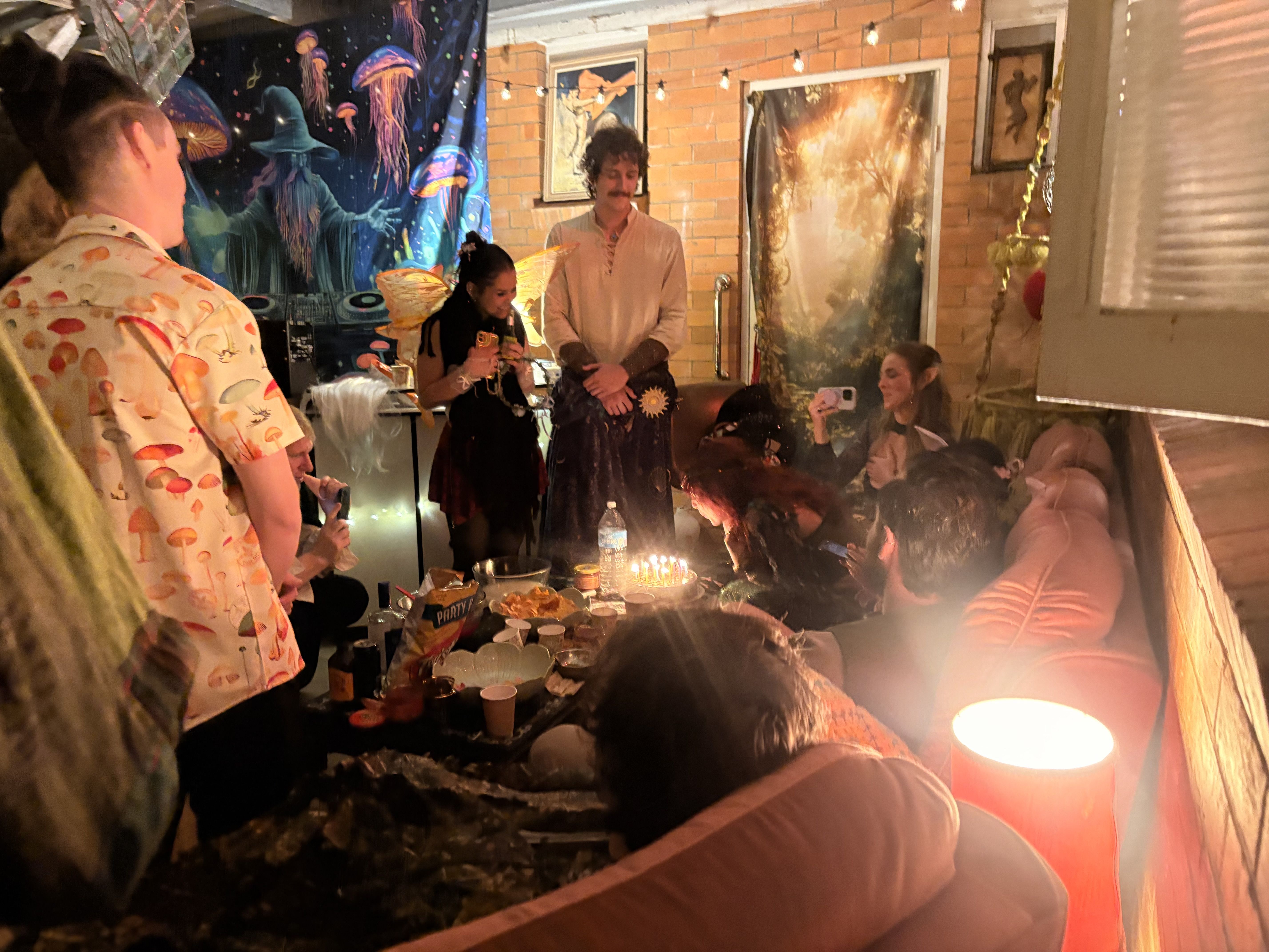 Costume party gathered around a candlelit cake