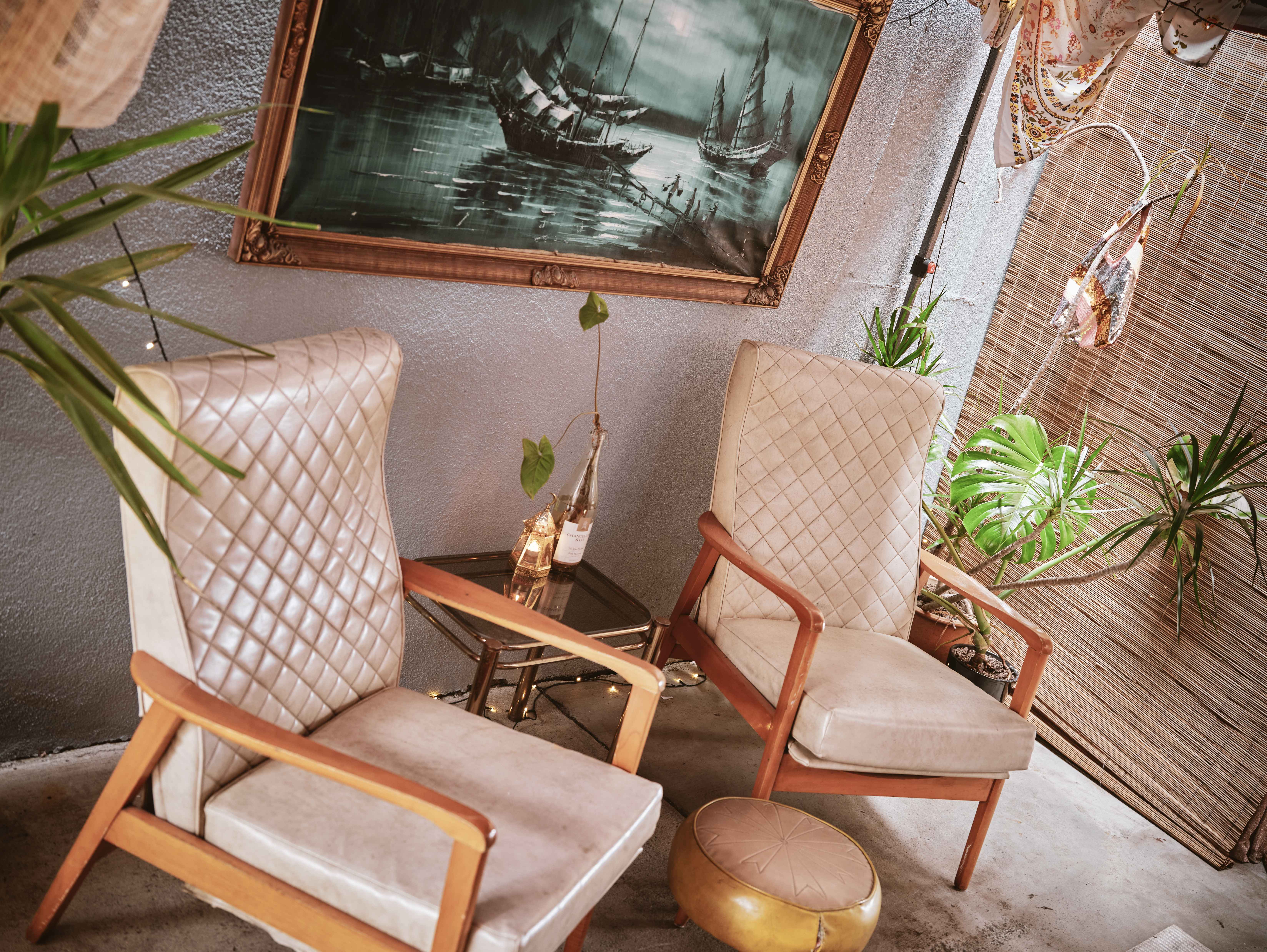 Sunny courtyard with fringed umbrella, green chairs and retro sofa